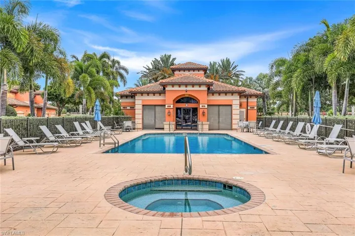 View of community swimming pool featuring a patio, a hot tub and club house