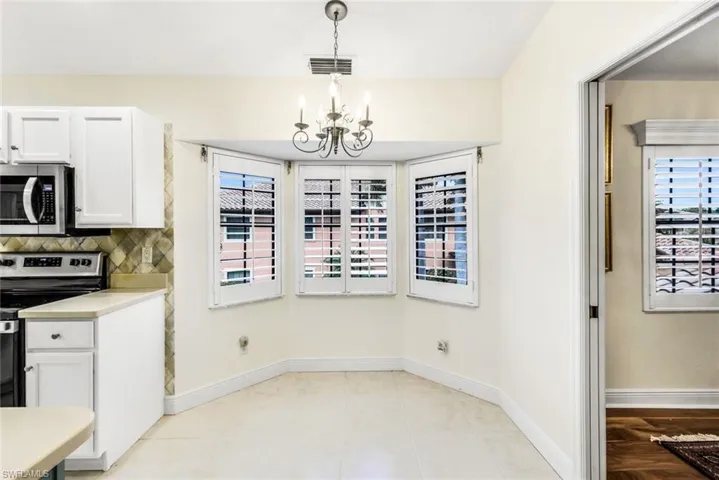 In kitchen, breakfast area featuring light tile floors, an inviting chandelier, and a healthy amount of sunlight