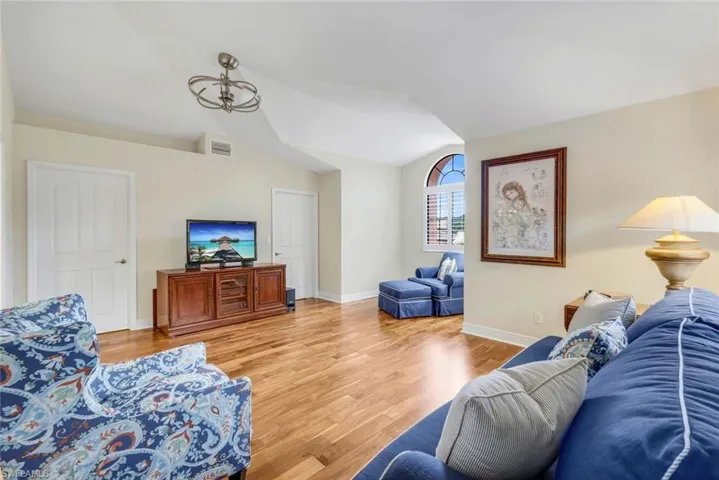 Guest bedroom featuring vaulted ceiling and wood flooring