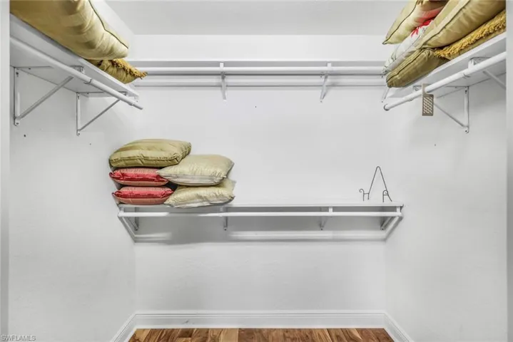 Primary walk in closet with wood floors