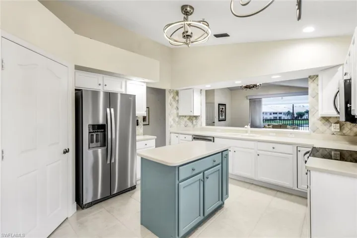 Kitchen with pendant lighting, new appliances with stainless steel finishes, a kitchen island, tasteful backsplash, and light tile flooring