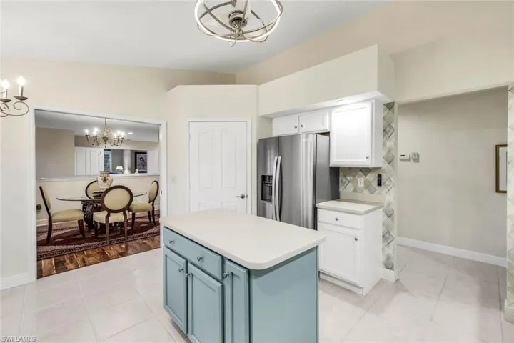 Kitchen with pendant lighting, new appliances with stainless steel finishes, a kitchen island, tasteful backsplash, and light tile flooring