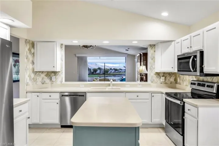 Kitchen with pendant lighting, new appliances with stainless steel finishes, a kitchen island, tasteful backsplash, and light tile flooring