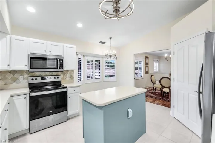 Kitchen with pendant lighting, new appliances with stainless steel finishes, a kitchen island, tasteful backsplash, and light tile flooring