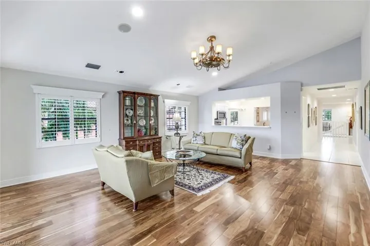 Living room with Acacia wood floors, a chandelier, and vaulted ceiling
