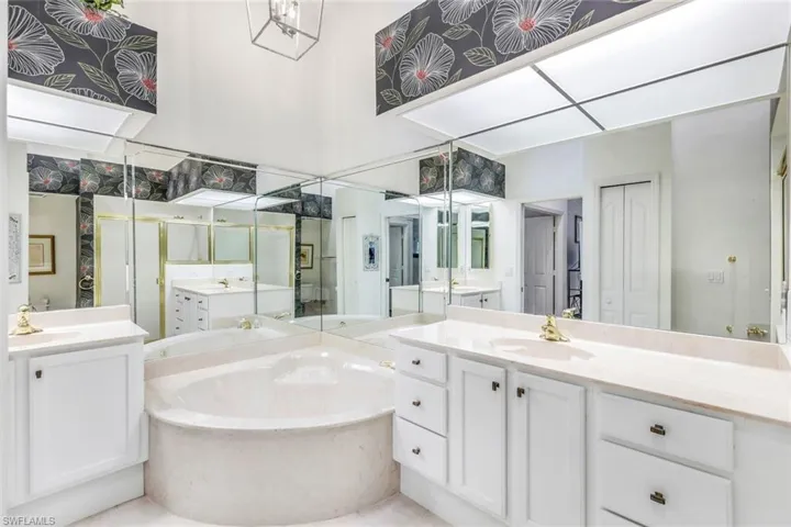 Primary bathroom with dual bowl vanity, walk in shower and soaking tub