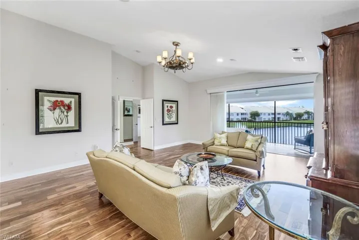 Living room with Acacia wood floors, a chandelier, and vaulted ceiling