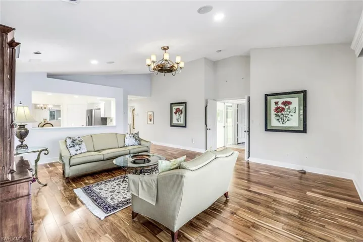 Living room with Acacia wood floors, a chandelier, and vaulted ceiling