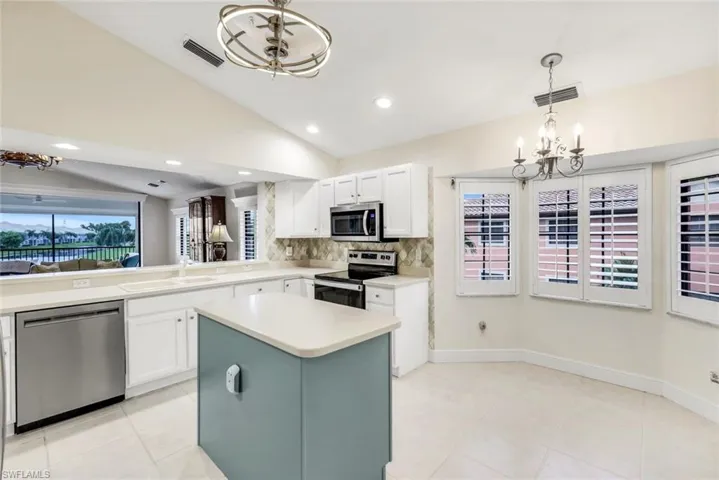 Kitchen with pendant lighting, new appliances with stainless steel finishes, a kitchen island, tasteful backsplash, and light tile flooring