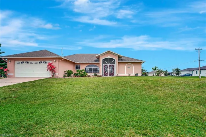 View of front of home featuring concrete driveway, an attached garage, a front lawn, and stucco siding