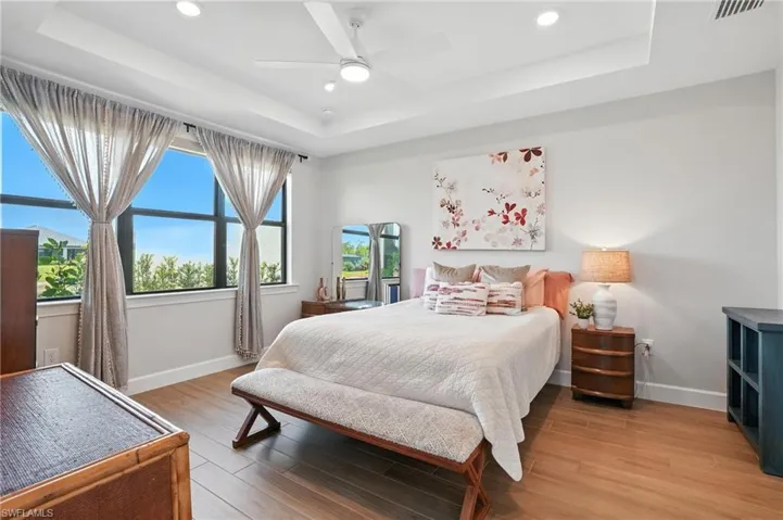 Bedroom featuring a raised ceiling, light wood-style flooring, recessed lighting, and ceiling fan