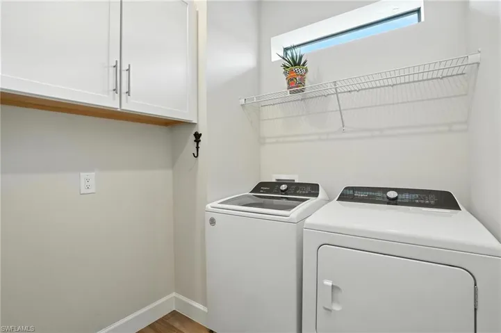 Laundry room with washer and dryer, cabinet space, and wood finished floors