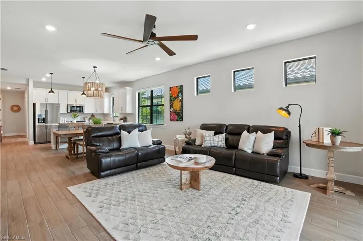 Living room with ceiling fan, light wood finished floors, recessed lighting, and a chandelier
