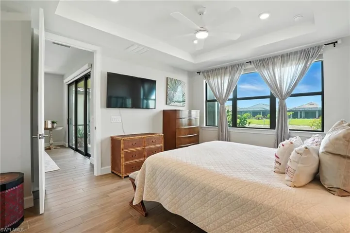 Bedroom featuring a raised ceiling, light wood-type flooring, recessed lighting, and a ceiling fan