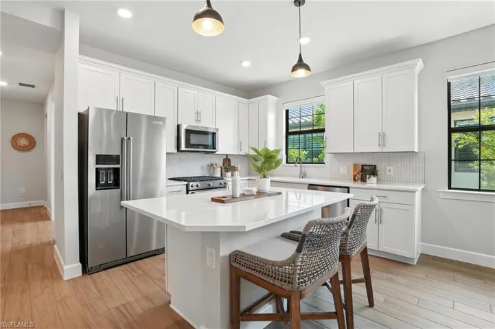 Kitchen featuring appliances with stainless steel finishes, tasteful backsplash, white cabinets, a kitchen island, and recessed lighting