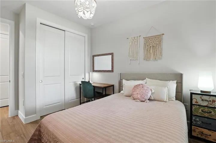 Bedroom featuring light wood-type flooring, a closet, and a chandelier