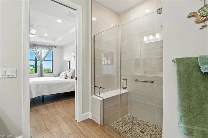 Bathroom with wood finished floors, a stall shower, ensuite bathroom, recessed lighting, and a raised ceiling