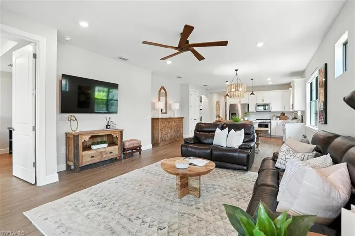 Living area featuring light wood-style floors, ceiling fan, recessed lighting, and a chandelier