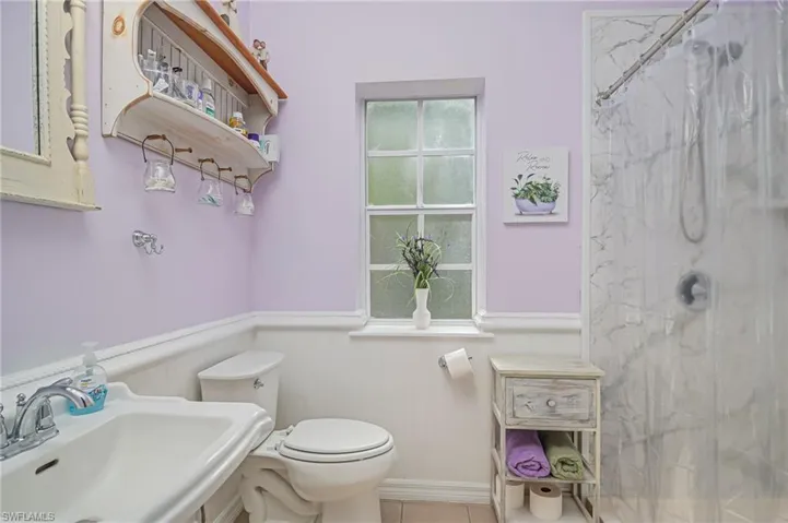 Guest bathroom with wainscoting, pedestal sink and walk in shower.