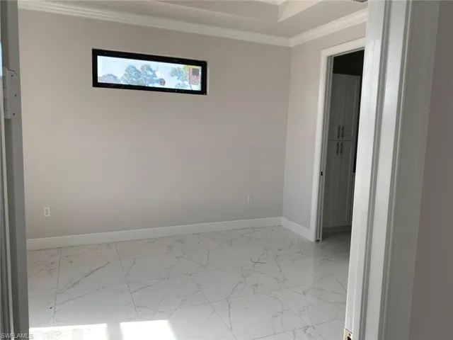 Empty room featuring light marble finish floors and crown molding