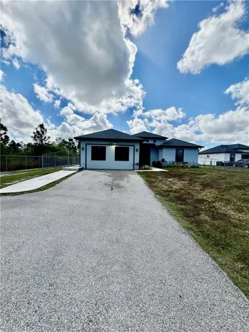 Single story home featuring driveway, a garage, and stucco siding