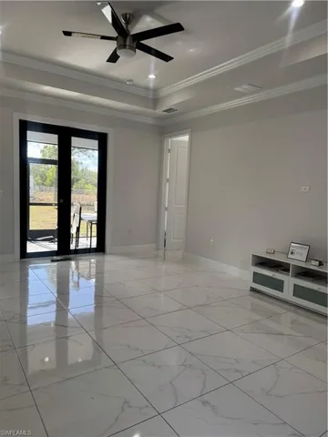 Empty room with a tray ceiling, french doors, crown molding, a ceiling fan, and recessed lighting