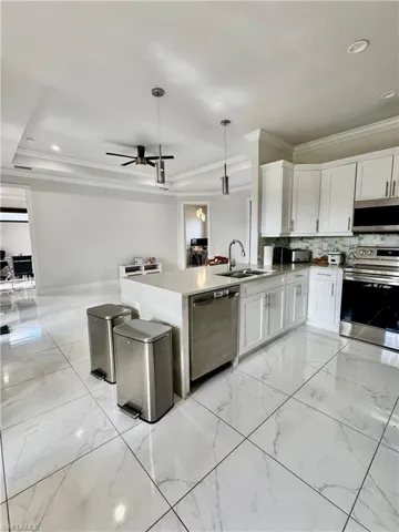 Kitchen with crown molding, stainless steel appliances, white cabinets, recessed lighting, and pendant lighting