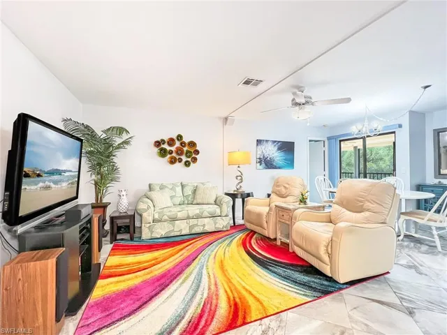 Living room featuring ceiling fan with notable chandelier