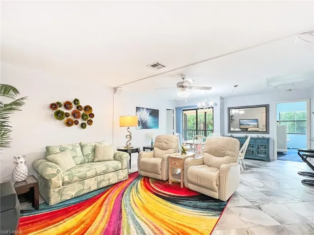 Living room with a wealth of natural light and ceiling fan with notable chandelier