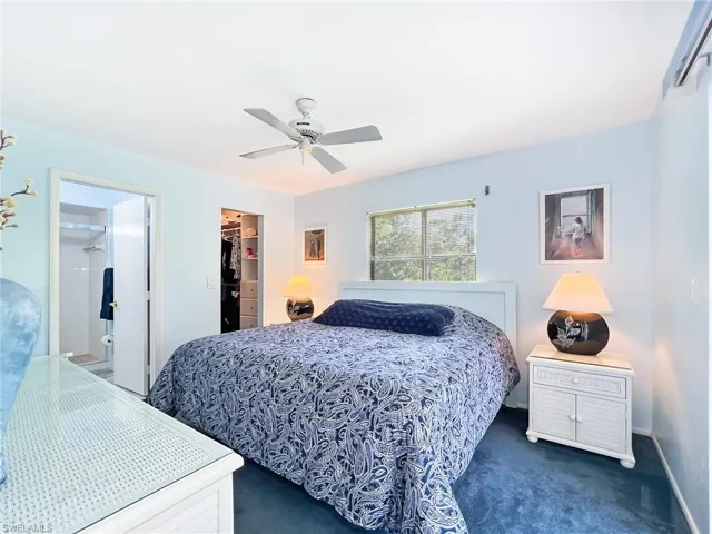 Carpeted bedroom with ceiling fan, a walk in closet, a closet, and ensuite bathroom