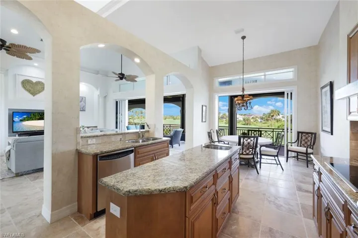 Kitchen featuring ceiling fan with notable chandelier, an island with sink, sink, and dishwasher
