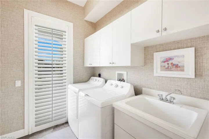 Laundry room with cabinets, light tile patterned flooring, sink, and independent washer and dryer