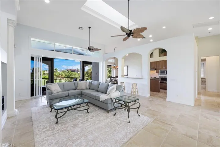 Living room featuring ceiling fan, a towering ceiling, and light tile patterned floors