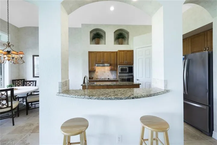 Kitchen featuring appliances with stainless steel finishes, backsplash, stone counters, and light tile patterned floors