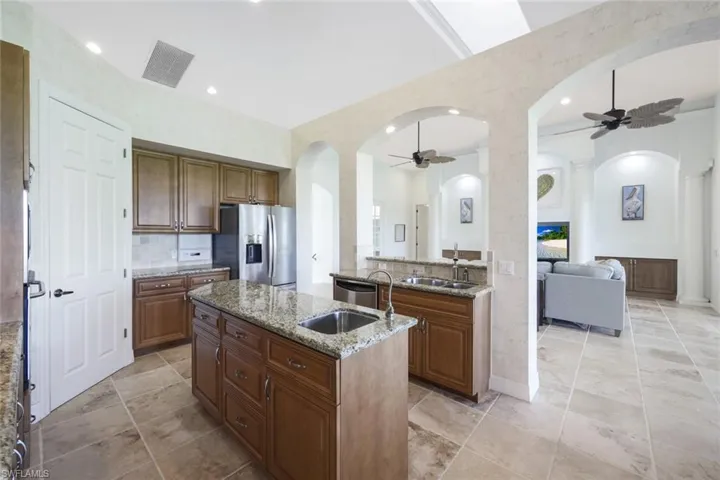 Kitchen with appliances with stainless steel finishes, a kitchen island with sink, light tile patterned floors, and ceiling fan