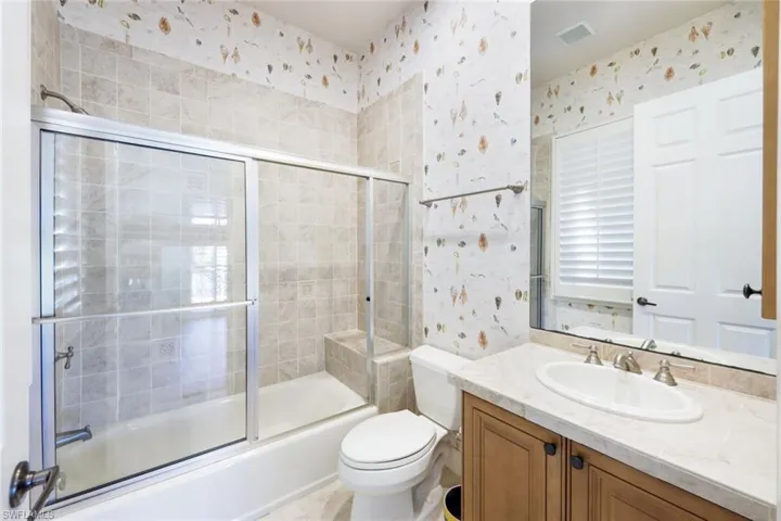 Full bathroom with vanity, combined bath / shower with glass door, and toilet