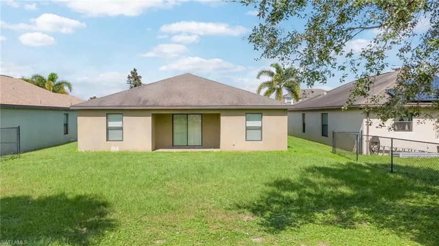 Stucco exterior featuring a hipped roof, sliding glass doors, and a fenced backyard