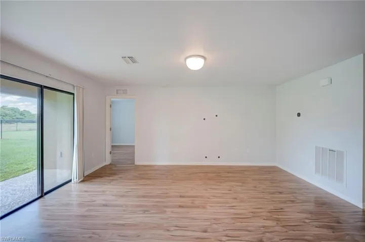 Open-concept interior featuring wood-finish flooring, a flush-mount ceiling light fixture, and large sliding glass doors providing outdoor access