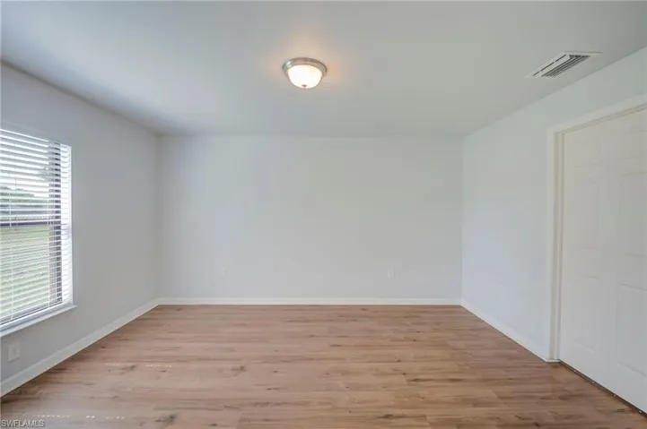 Neutral-toned room featuring wood-finish flooring, a flush-mount ceiling light fixture, and a single-panel interior door