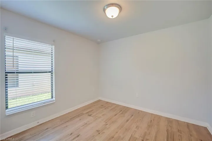 Room featuring wood-finish flooring, a single-window configuration with horizontal blinds, and a flush-mount ceiling light fixture