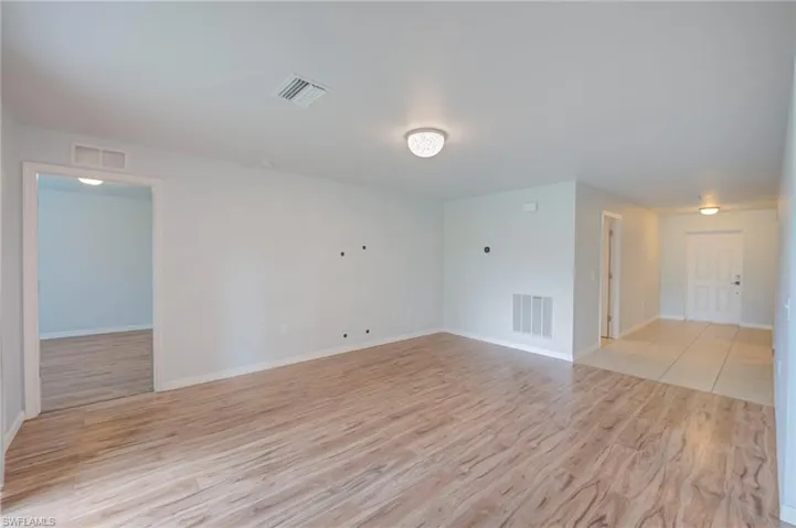 Open-concept interior featuring wood-finish flooring, ceramic tile entryway, and flush-mount ceiling lighting
