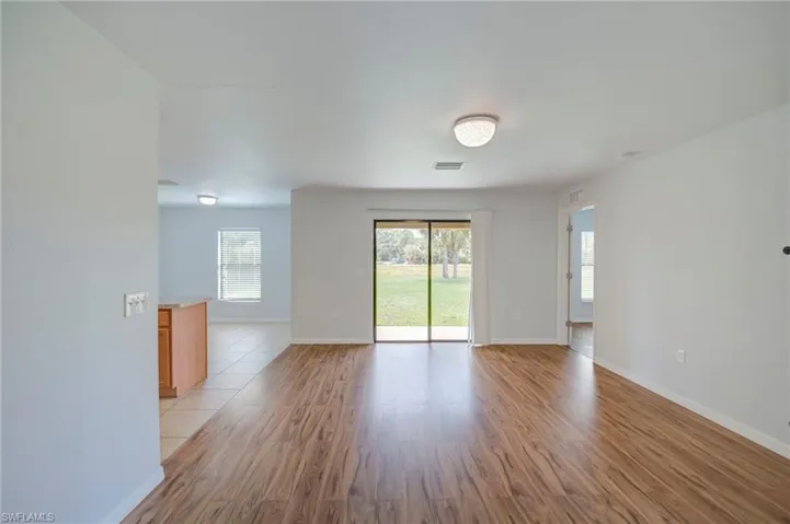 Interior space featuring wood-finish flooring, sliding glass doors, neutral wall color, and flush-mount lighting fixtures