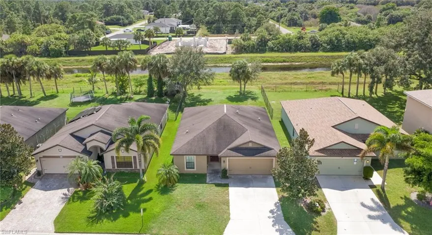 Single-story residence featuring a multi-hip roof, attached two-car garage, concrete driveway, and a landscaped lot situated along a water feature
