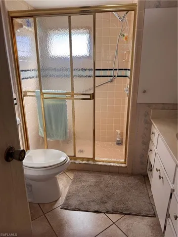 Full bath with a stall shower, vanity, and light tile patterned floors