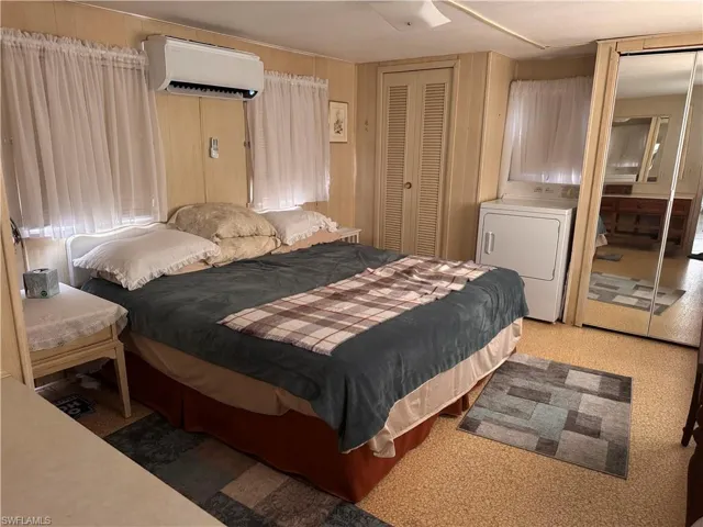 Carpeted bedroom  clothes dryer, a closet, a mini-split unit AC, and paneled walls