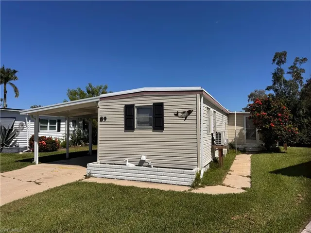 View of side of home featuring a yard, driveway, and an attached carport