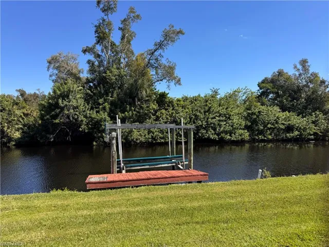 Dock area with boat lift, a yard, and a water view