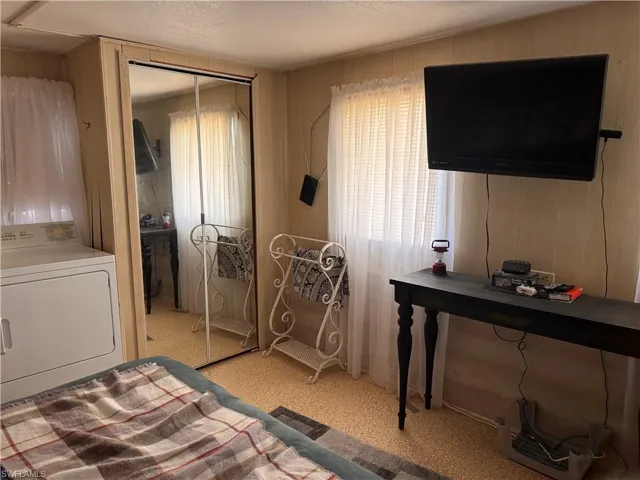 Bedroom with dryer, closets, tv, paneled walls.
