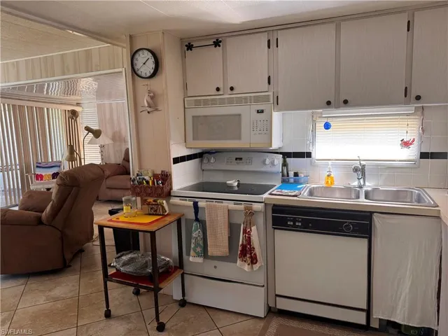 Kitchen featuring white appliances, light tile patterned floors, open floor plan, light countertops, and tasteful backsplash