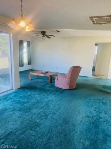 Living area with ceiling fan, a textured ceiling, and carpet flooring